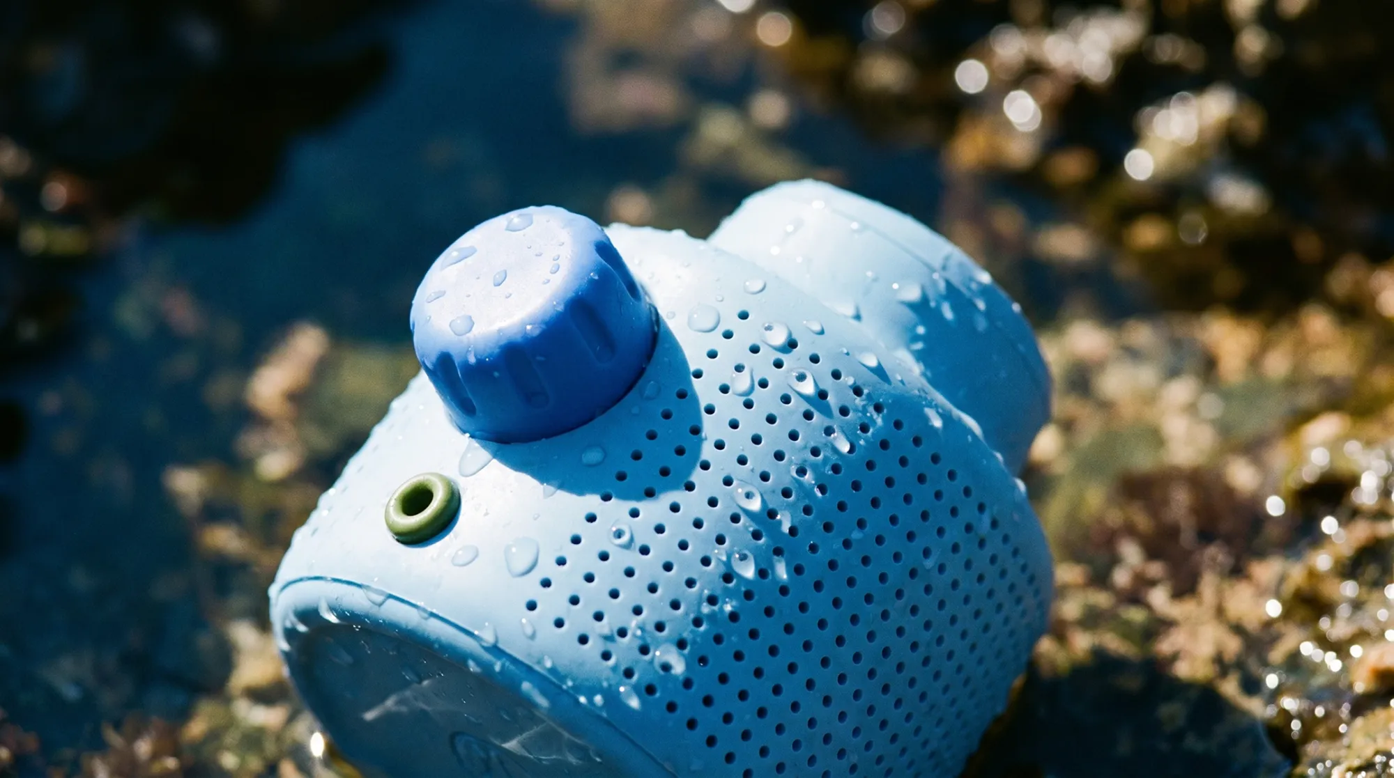 Close-up of a mur mur speaker in shallow pond water with droplets on its surface